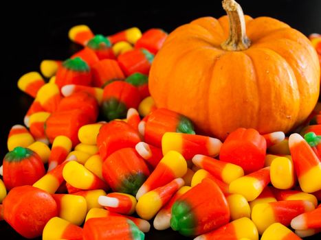 Halloween candy corn and pumpkin candies on black background.