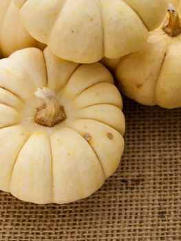 Small white pumpkins on burlap fabric.