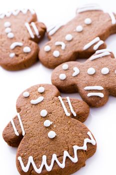 Homemade gingerbread cookies decorated with white icing on white background.