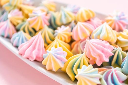 Multicolored unicorn meringue cookies on a white serving plate.