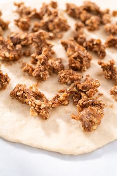 Preparing cinnamon dessert pizza on a baking sheet lined with parchment paper.