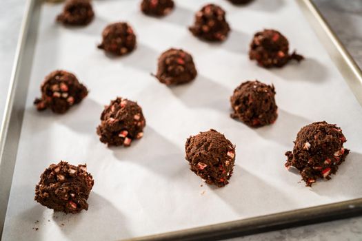 Scooping chocolate cookie dough with dough scoop to bake chocolate cookies with peppermint chips.