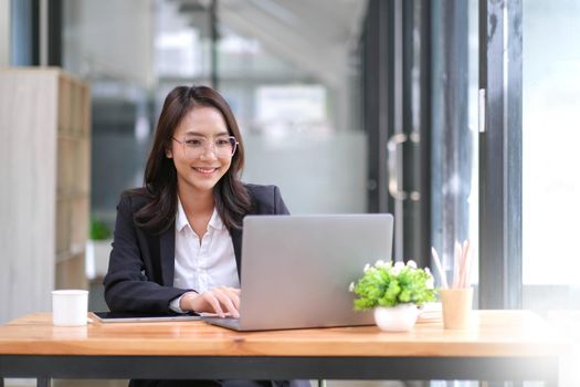 Portrait of Asian young female working on laptop at office.