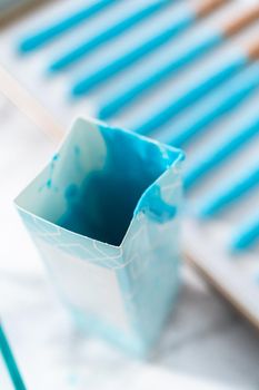 Dipping in pretzel rods into melted chocolate to prepare mermaid chocolate pretzel rods.
