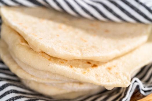Stack of freshly baked flatbread wrapped in a kitchen towel.