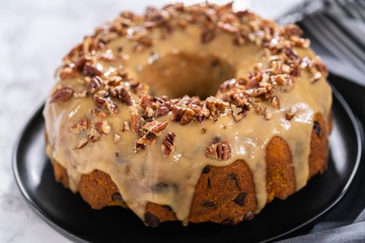 Freshly baked chocolate pumpkin bundt cake with toffee glaze topped with toasted pecans.