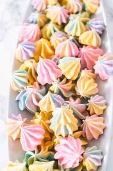 Multicolored unicorn meringue cookies on a white serving plate.