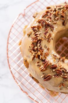 Frosting pumpkin bundt cake with a toffee glaze and garnish with toasted pecans.