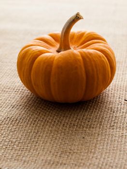 Small orange pumpkins on burlap fabric.