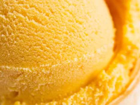 Scoop of gourmet pumpkin gelato in cake cone on white background.