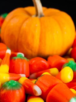 Halloween candy corn and pumpkin candies on black background.