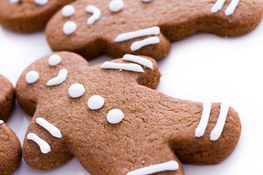 Homemade gingerbread cookies decorated with white icing on white background.