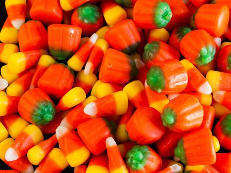 Halloween candy corn and pumpkin candies on black background.