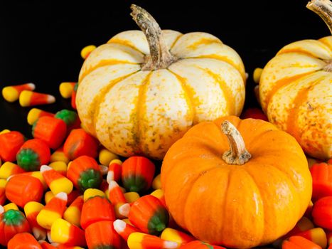 Halloween candy corn and pumpkin candies on black background.