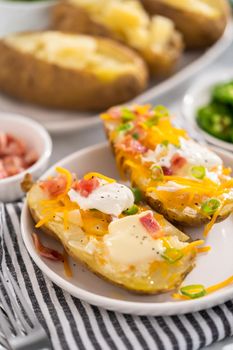 Pressure Cooker Baked Potatoes. Garnished large baked potatoes with butter, sour cream, cheese, and bacon bits on a white plate.