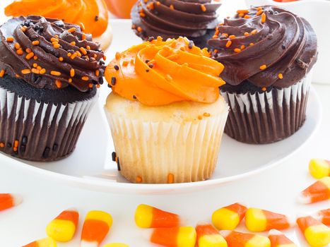 Halloween cupcakes with orange and black icing on white plate.