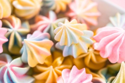 Multicolored unicorn meringue cookies on a white serving plate.
