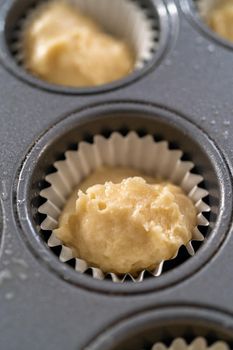 Scooping cupcake batter with dough scoop into a baking pan with liners to bake American flag mini cupcakes.