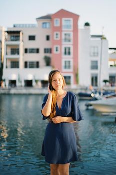 Young woman stands on the pier against the background of a multi-colored building. High quality photo