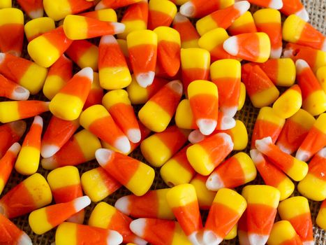 Traditional Halloween candies candy corn on burlap fabric.