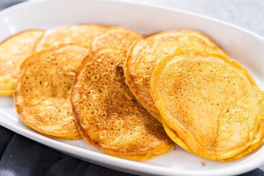 Freshly made pumpkin pancakes on a white serving plate.