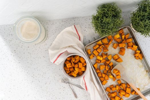 Flat lay. Serving oven-roasted sweet potatoes in a white ceramic bowl.