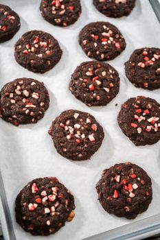 Cooling freshly baked chocolate cookies with peppermint chips on a kitchen counter.