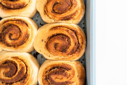Freshly baked cinnamon rolls in a blue baking pan.