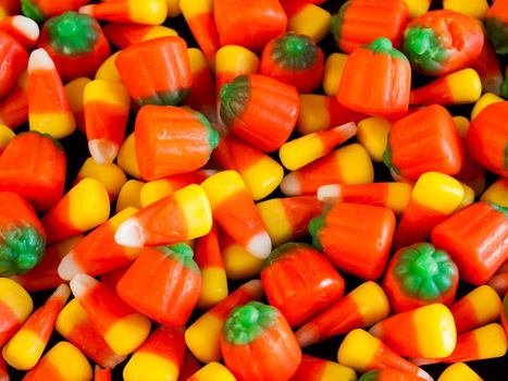 Halloween candy corn and pumpkin candies on black background.