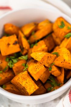 Serving oven-roasted sweet potatoes in a white ceramic bowl.
