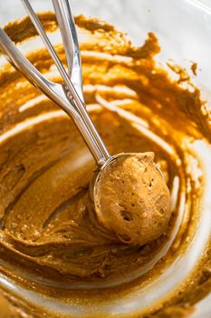Scooping cupcake batter with a dough scoop into cupcake foil liners to bake gingerbread cupcakes.