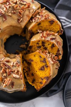 Slicing homemade chocolate pumpkin bundt cake with toffee glaze.