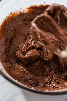 Mixing ingredients in a large glass mixing bowl to bake red velvet bundt cake with cream cheese glaze.