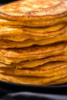 Stack of fresh pumpkin pancakes on a black plate.