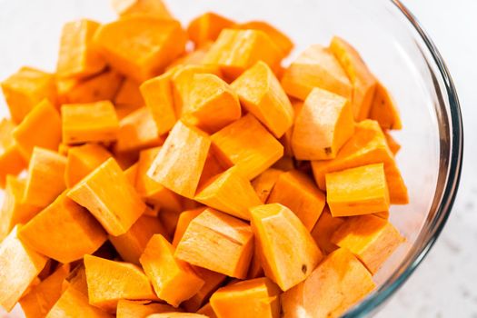 Seasoning cubed sweet potatoes to make oven-roasted sweet potatoes.