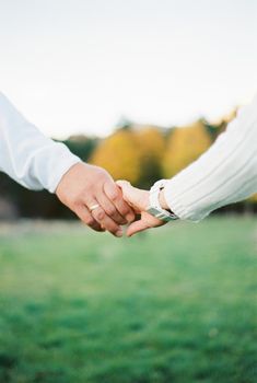 Man hand holds woman hand on a background of green grass. High quality photo