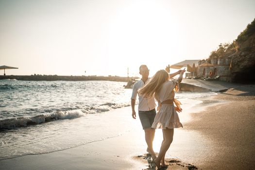 A couple in love is walking on the beach near the sea. Young family at sunset by the mediterranean sea. Summer vacation concept