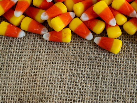 Traditional Halloween candies candy corn on burlap fabric.