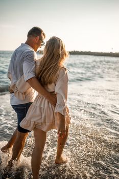 Summer holidays and travel. Sexy woman and man in sea water at sunset. Loving couple relax on the sunrise beach. Love relationship of a couple enjoying a summer day together