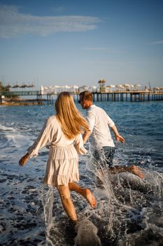 romantic young couple in love together on the sand walks along the beach of the Mediterranean sea. Summer vacation in a warm country.