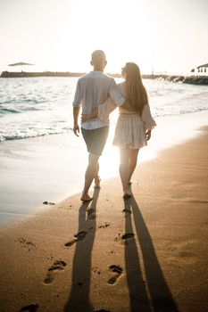 Summer holidays and travel. Sexy woman and man in sea water at sunset. Loving couple relax on the sunrise beach. Love relationship of a couple enjoying a summer day together. Selective focus