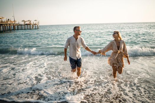 Happy couple by the sea. Honeymoon lovers. Man and woman on the island. Beautiful couple having fun on the seashore. Happy couple on vacation. Man and woman by the sea.