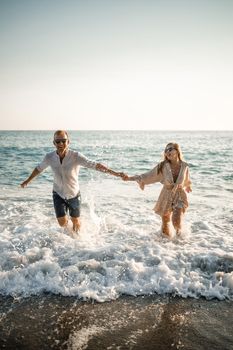 Happy couple by the sea. Honeymoon lovers. Man and woman on the island. Beautiful couple having fun on the seashore. Happy couple on vacation. Man and woman by the sea.