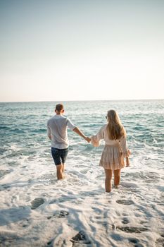 Happy couple by the sea. Honeymoon lovers. Man and woman on the island. Beautiful couple having fun on the seashore. Happy couple on vacation. Man and woman by the sea.