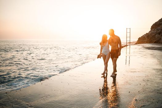 Romantic young couple in love walking together at sunset along the Mediterranean beach. Summer vacation in a warm country. Happy married couple on vacation in Turkey. Selective focus