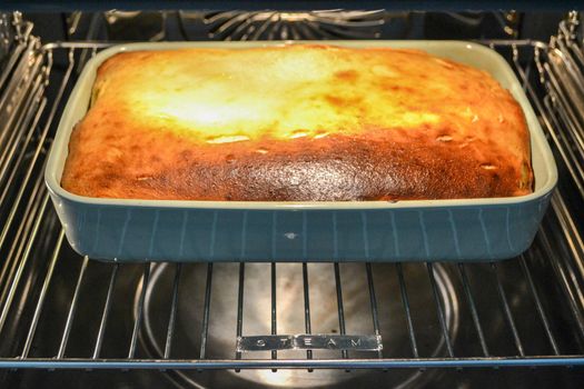 Cottage cheese casserole with raspberries and hazelnuts in a glass form is baked in the oven. Closeup. High quality photo