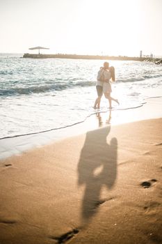 Summer holidays and travel. Sexy woman and man in sea water at sunset. Loving couple relax on the sunrise beach. Love relationship of a couple enjoying a summer day together. Selective focus