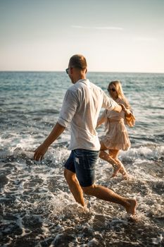 romantic young couple in love together on the sand walks along the beach of the Mediterranean sea. Summer vacation in a warm country. Selective focus