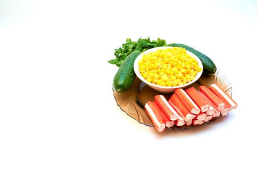 a cold dish of various mixtures of raw or cooked vegetables, usually seasoned with oil, vinegar, or other dressing. A set for a delicious healthy salad. Cucumbers, corn, crab sticks and greenery