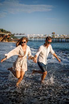 romantic young couple in love together on the sand walks along the beach of the Mediterranean sea. Summer vacation in a warm country.